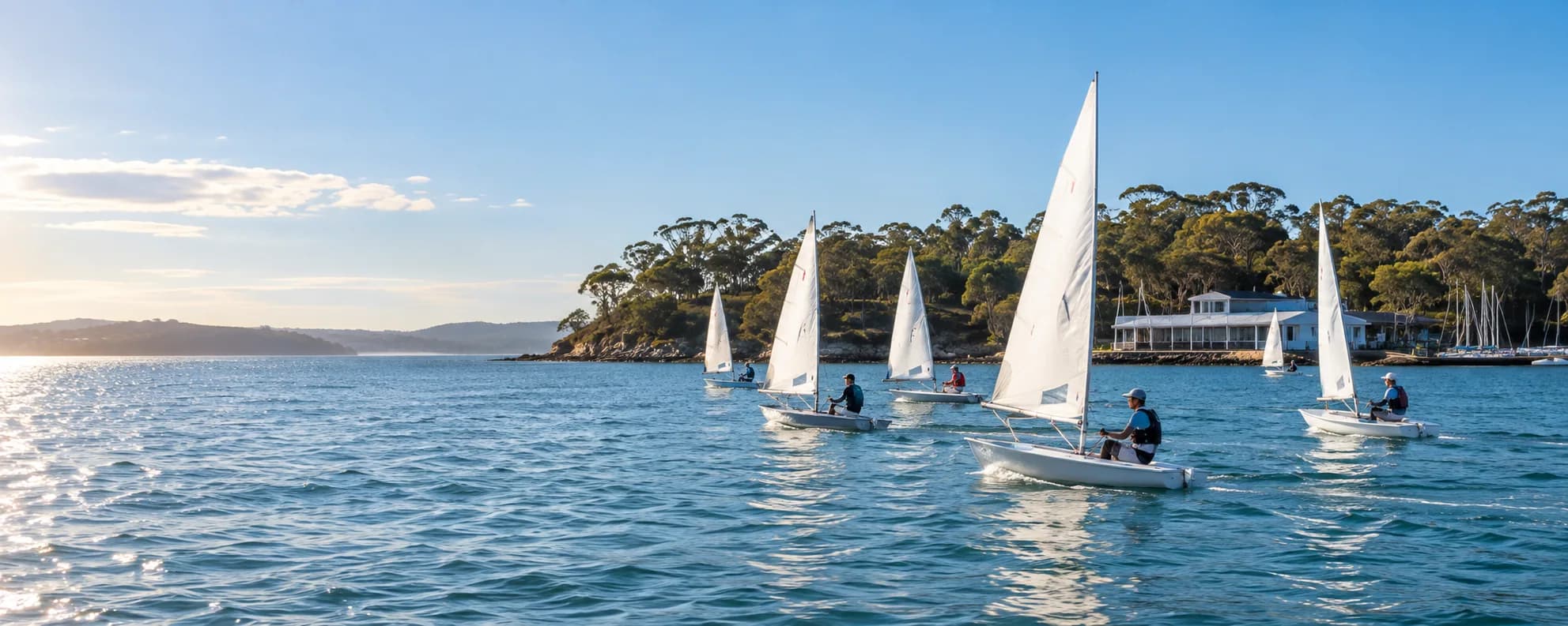 Small dinghies sailing together on an Australian bay near a waterfront club